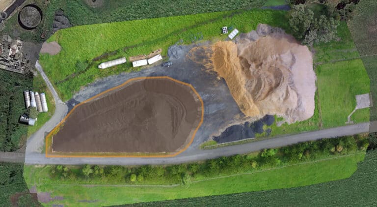 An aerial view of a field with a large pile of dirt.