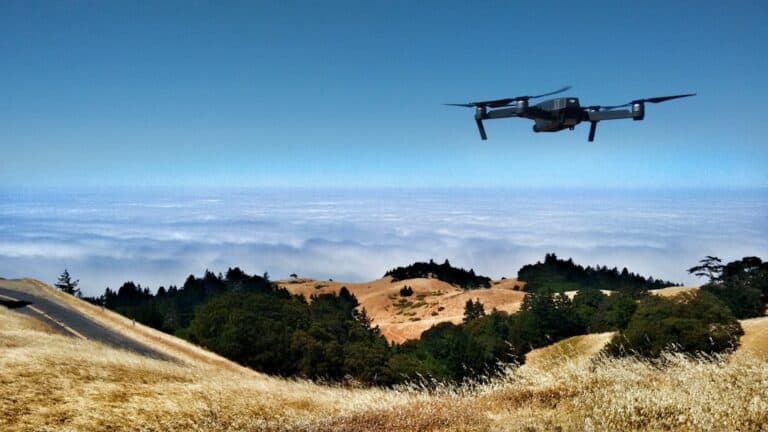 A drone flying over a hill with clouds in the background.