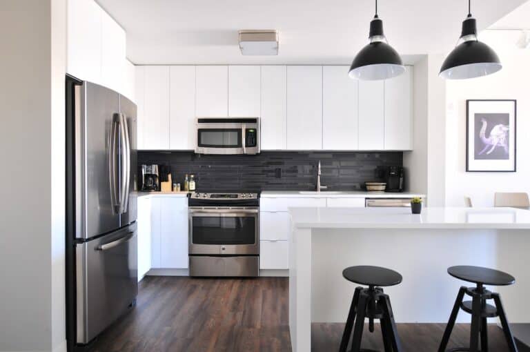 A kitchen with black and white cabinets and stools.