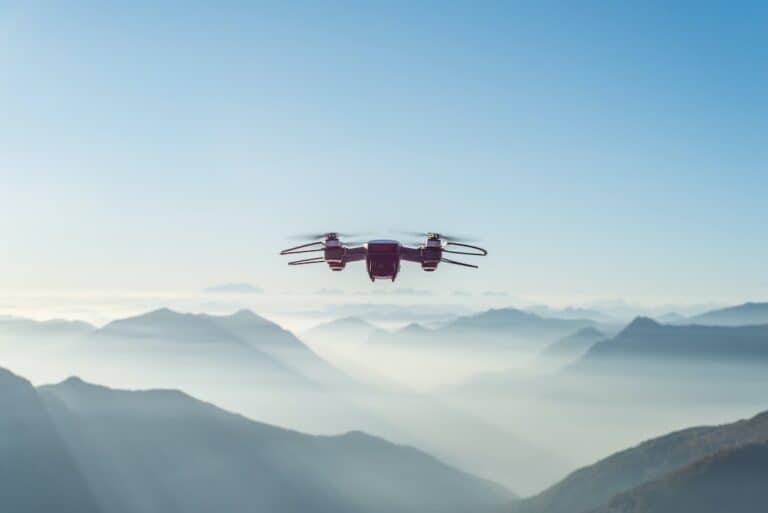 A small drone flying over a mountain range.