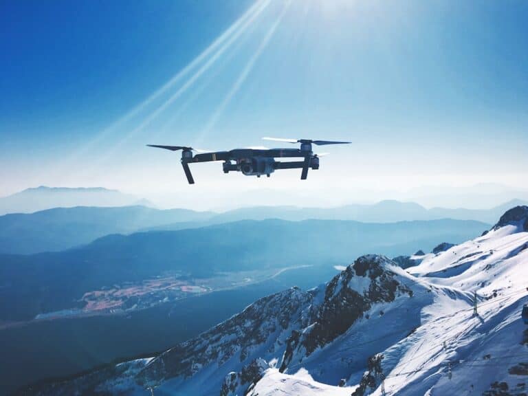 A drone flying over a snow covered mountain.