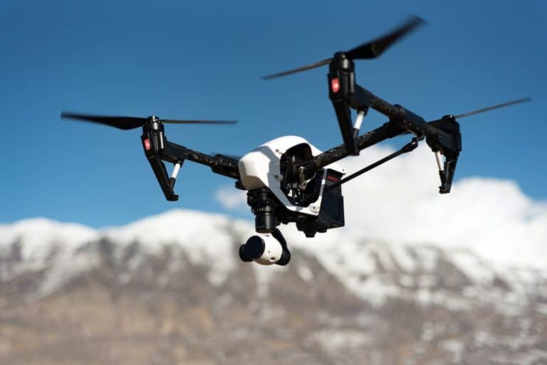 Quadcopter drone flying over snowy mountains.