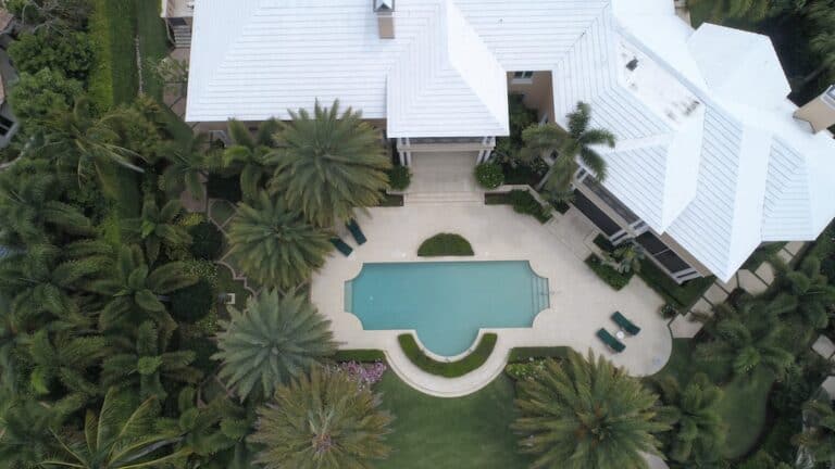 An aerial view of a home with a pool and palm trees.