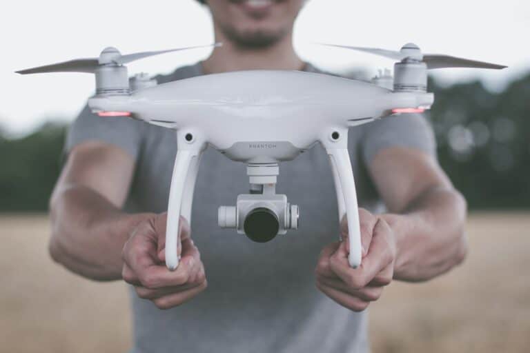 A man holding a dji phantom drone in a field.